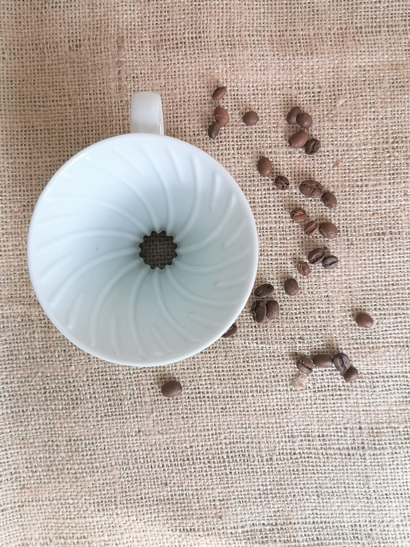 Hario V60 Keramikfilter, Porzellan Größe 02 weiß auf Kaffeesack mit Kaffeebohnen
